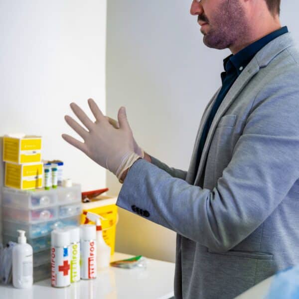 Dr Juan Bester putting on medical gloves at LightSculpt Green Point in Cape Town, reflecting the clinical safety and anatomical precision required in professional medical aesthetics.